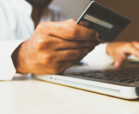 hand holding credit card above laptop keyboard